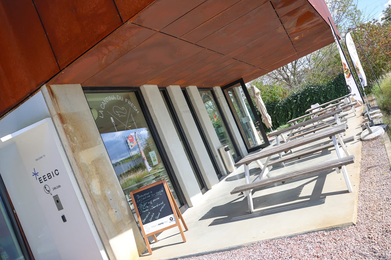 La terrasse de la cantine, tables blanches le long de la façade de l’EEBIC